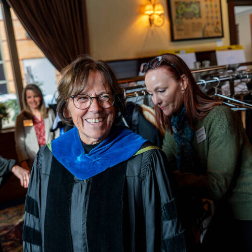 Theresa Bacon-Baguley smiles as Justine Rau Kibet helps during robing at the Faculty Awards Convocation in February, when Bacon-Baguley earned a Niemeyer Award.